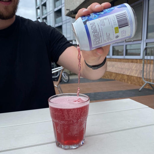 A refreshing can of All About Kombucha's sparkling berry kombucha being poured into a glass outdoors — fizzy, vibrant, and packed with probiotics.
