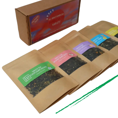 All About Kombucha tea variety pack featuring five kraft paper pouches of loose leaf tea blends, including elderflower oolong, berry bliss, and peach blossom, alongside branded packaging box