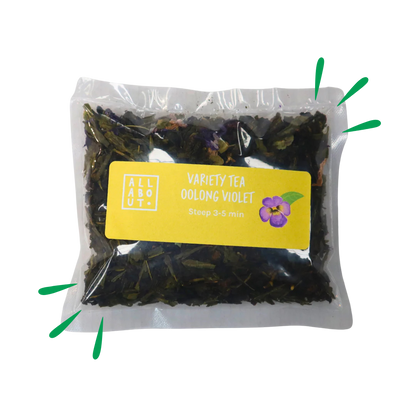 All About Kombucha variety tea pouch labeled Oolong Violet in a clear steeping pack with yellow label and violet flower illustration, containing floral loose tea blend.